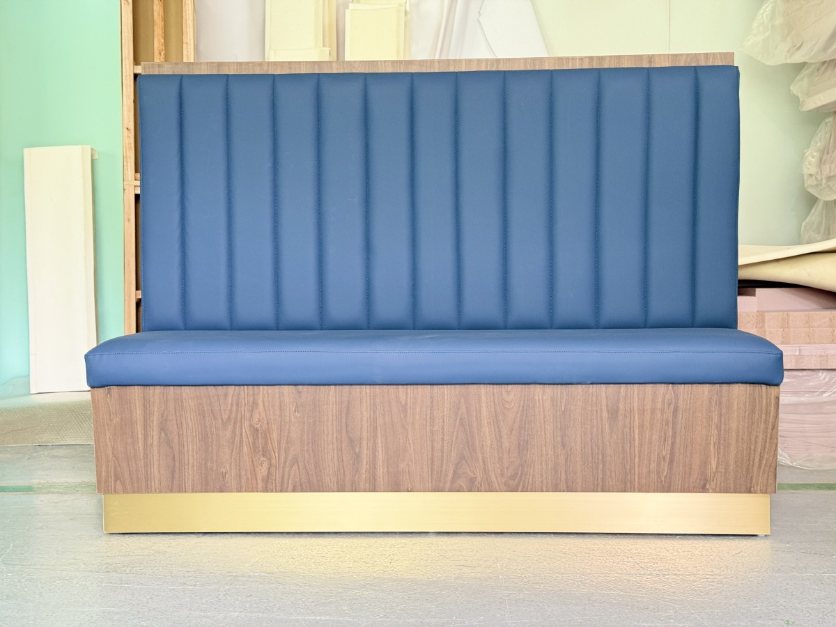 Modern café booth seating with blue vinyl upholstery and wood base with brass kick plate