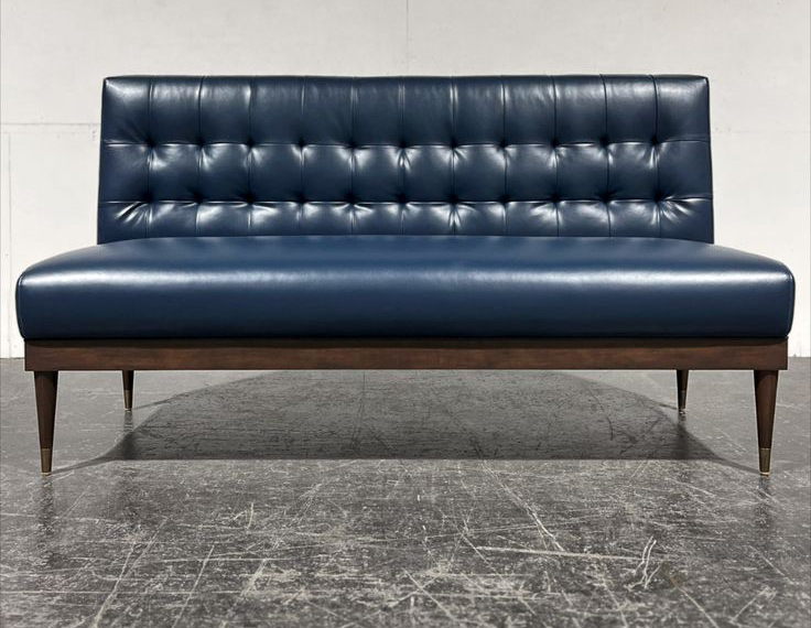Commercial dining booth with navy leather upholstery and brass-capped wood legs