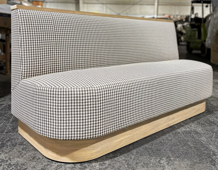 Upholstered hotel banquette seating with houndstooth fabric and wood base