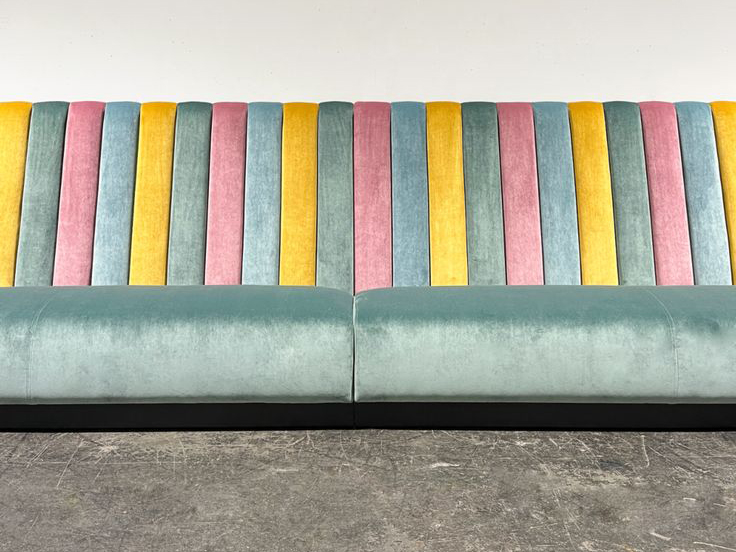 Long upholstered commercial banquette seating in pastel tones