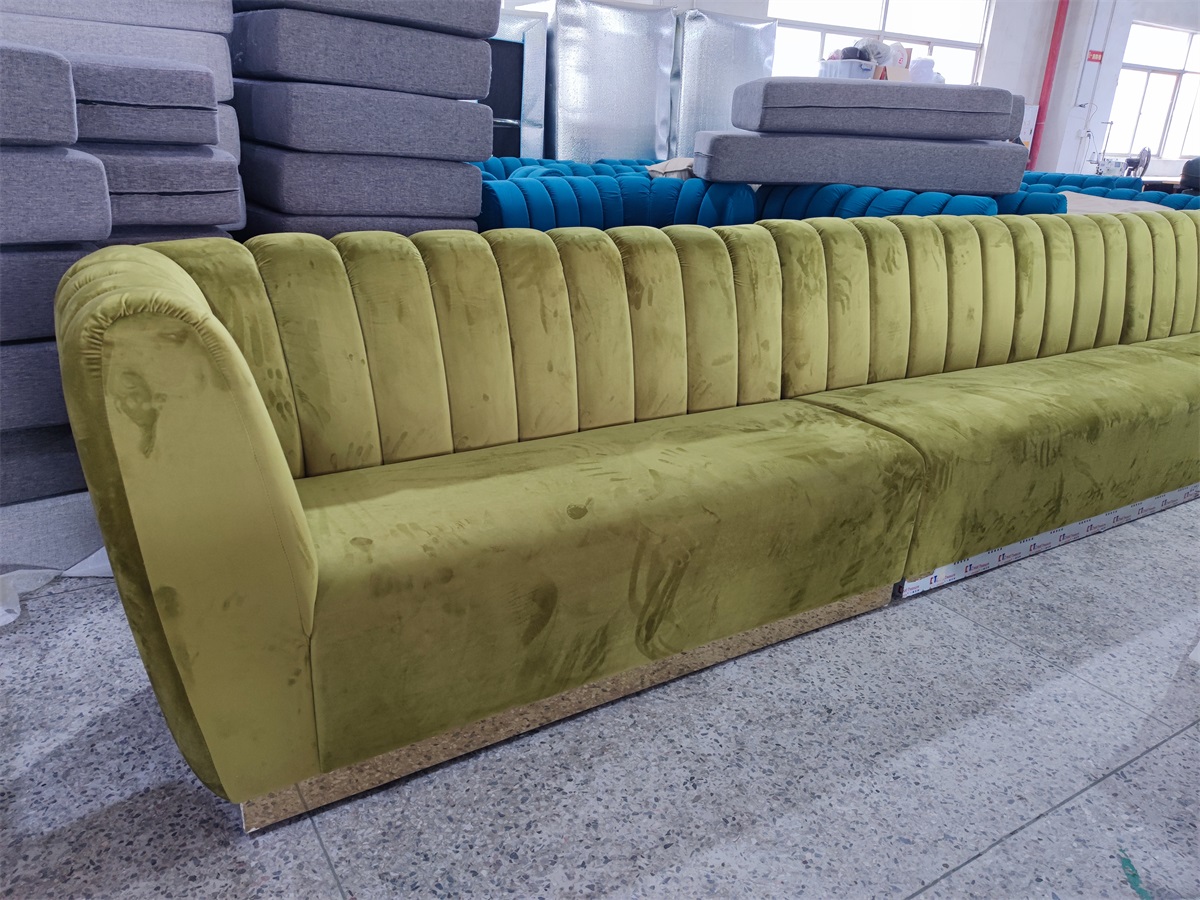 Long green velvet banquette with channel tufting in a factory setting
